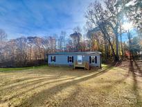 Gray mobile home with black shutters and wood deck, nestled in a wooded area at 46 Kidd And Brown Rd, Hiddenite, NC 28636