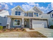 Two-story house with gray siding, stone accents, and a two-car garage at 5103 Heathland Dr # 50, Charlotte, NC 28215