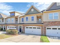 Tan, three-story townhome with white garage doors and dark brown front door at 4146 La Crema Dr, Charlotte, NC 28214