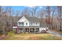 Two-story house with gray siding, stone accents, and a wraparound porch at 10827 Hadrians Walk Ct, Mint Hill, NC 28227