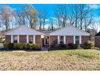 Brick ranch house with white trim, landscaping, and a spacious yard at 5021 Prestwick Ln, Charlotte, NC 28212