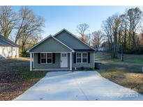 Charming green two-story home with a concrete driveway and front yard at 1014 Kansas St, Kannapolis, NC 28083