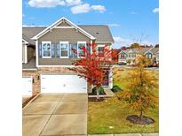 Two-story townhome with gray siding, a white garage door, and autumnal landscaping at 2471 Palmdale Walk Dr # 107, Fort Mill, SC 29708