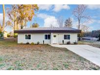 Newly built light gray house with dark metal roof, landscaping, and a paved driveway at 3035 Fallswood Dr, Gastonia, NC 28052