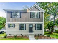 Two-story house featuring gray and beige siding, a dark door, and landscaping at 358 Camden Nw Ct, Concord, NC 28027