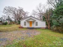 Charming white home with a bright yellow door and green lawn at 208 Oakland Dr, Lowell, NC 28098