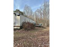 Exterior view of a manufactured home with a wooden deck, surrounded by trees and dry leaves at 206 Rocky Top Rd, Taylorsville, NC 28681