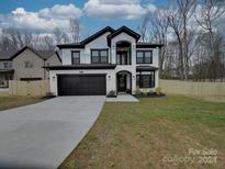 Two-story house with white and black accents, a two-car garage, and a landscaped yard at 1308 Pleasant Plains Rd, Matthews, NC 28105