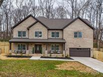 Two-story brick home with a front porch, attached garage, and landscaping at 1312 Pleasant Plains Rd, Matthews, NC 28105