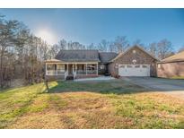 Brick ranch house with front porch, two-car garage, and landscaped yard at 1350 Kensington Cir, Newton, NC 28658