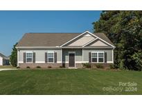 Newly constructed ranch home with gray siding, brick accents, and a well-manicured lawn at 6316 Honor Ave, Midland, NC 28107