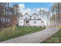 Two-story farmhouse features a white exterior, landscaping, and a long driveway at 4171 Island Fox Ln, Denver, NC 28037