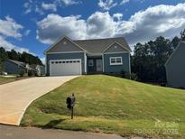 Charming one-story home with gray and blue siding, attached garage, and manicured lawn at 9405 Tradewinds Ct, Lancaster, SC 29720