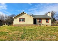 Ranch home with light yellow siding, red trim, and a grassy yard at 7306 Bramblewood Dr, Charlotte, NC 28217