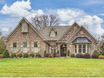 Brick and stone one-story house with a landscaped lawn and a welcoming front porch at 150 Abbington Pl, Locust, NC 28097