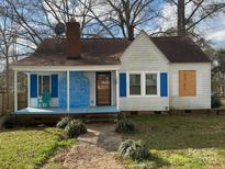 White house with blue shutters, covered porch, and a brick fireplace accent at 110 Courtland St, Chester, SC 29706