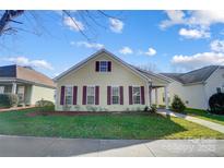 Eye-catching yellow house with maroon accents and a manicured lawn at 10117 Bishops Gate Blvd, Pineville, NC 28134