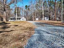 Ranch home with front porch and detached garage, nestled in a wooded setting at 38899 Dalton Ln, Albemarle, NC 28001