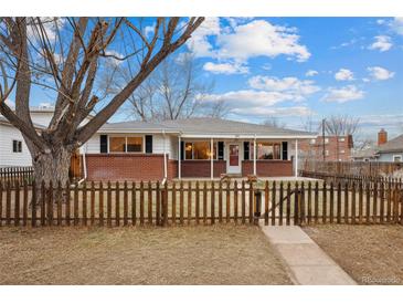 Brick ranch home with covered porch, picket fence, and landscaped yard at 4109 S Acoma St, Englewood, CO 80110