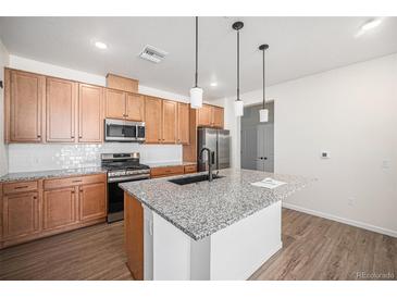 Modern kitchen with light wood cabinets and granite island at 6153 N Ceylon St # 303, Denver, CO 80249