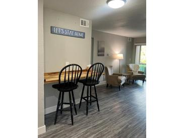 Breakfast bar with two black stools, gray walls, and wood countertop at 4899 S Dudley St # 1E, Littleton, CO 80123