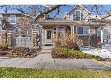 Inviting exterior of a two-story townhome with stone accents and landscaping at 7353 Norfolk Pl, Castle Pines, CO 80108
