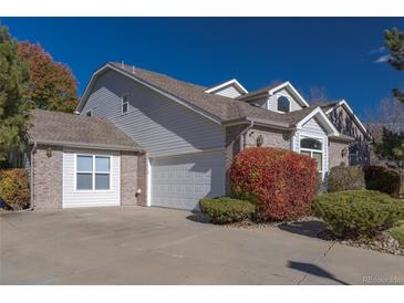 Charming two-story home with a gray and brick exterior, white garage door, and landscaped front yard at 877 Home Farm Ave, Westminster, CO 80234