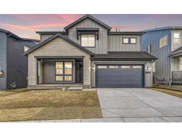 Two-story modern home with gray siding, stone accents, and a two-car garage at 6656 Bridle Creek Pt, Castle Pines, CO 80108