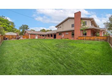 House's back with a large grassy yard and wooden fence at 10101 W 72Nd Ave, Arvada, CO 80005