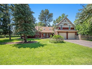 Red two-story house with a large yard and attached two-car garage at 7893 Hill Crest Dr, Louviers, CO 80131