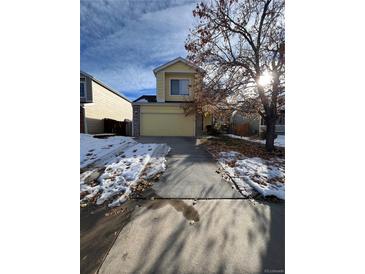 Two-story yellow house with a snow-covered driveway and landscaping at 21620 E Crestline Ln, Centennial, CO 80015