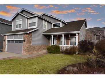 Two-story house with gray siding, stone accents, and a landscaped lawn at 9362 Autumn Ash Ct, Highlands Ranch, CO 80126