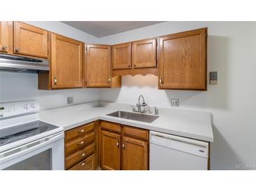 Kitchen with wood cabinets, white appliances, and light countertops at 3144 S Wheeling Way # 209, Aurora, CO 80014