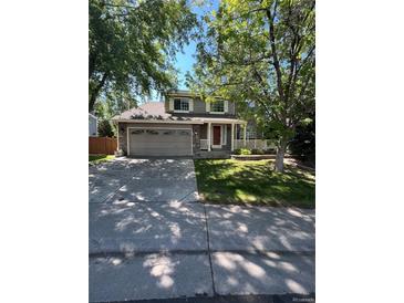 Two-story house with gray siding, attached garage, and mature trees in the front yard at 16580 E Hialeah Dr, Centennial, CO 80015