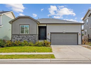 Ranch-style home with a gray exterior, stone accents, and a two-car garage at 9674 Truckee St, Commerce City, CO 80022