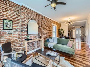 Living room features exposed brick wall, green couch, and hardwood floors at 3960 Kalamath St, Denver, CO 80211