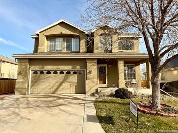 Two-story house with tan siding, a large garage, and a landscaped front yard at 12578 Dexter Way, Thornton, CO 80241