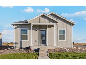 A charming one-story home with light gray siding and a welcoming front porch at 3012 Oxley St, Strasburg, CO 80136
