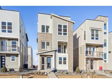 Modern three-story townhome with light-colored brick and siding at 1281 Penner Dr, Erie, CO 80026