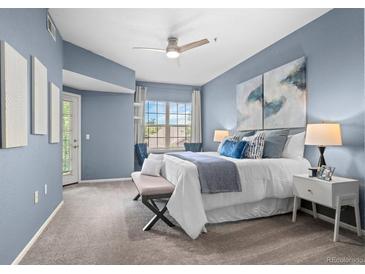 Large, light blue bedroom with a ceiling fan, private balcony, and plush carpet at 10733 Twenty Mile Rd # 204, Parker, CO 80134