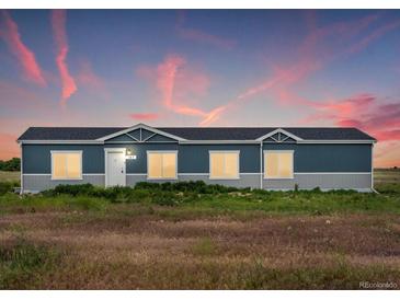 Ranch style home with blue exterior, and landscaped yard at 165 S County Road 197, Byers, CO 80103