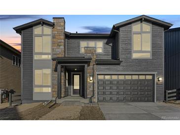 Two-story home with gray siding, stone accents, and a two-car garage at 6664 Bridle Creek Pt, Castle Pines, CO 80108