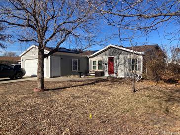 Ranch style home with gray siding, attached garage, and a spacious yard at 1103 Stage Dr, Fort Lupton, CO 80621