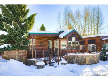 Rustic log cabin exterior with snow covered deck and stonework at 85 Revett Dr # 73, Breckenridge, CO 80424