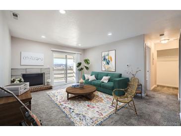 Bright living room with fireplace, balcony access, and mountain views at 519 Wright St # 304, Lakewood, CO 80228