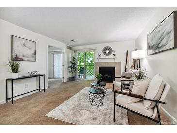 Living room with fireplace, balcony access, and neutral decor at 8813 Colorado Blvd # 207, Thornton, CO 80229