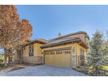 Exterior of house with stone accents and a paved driveway.Landscaped with trees at 7818 Vallagio Ln, Englewood, CO 80112