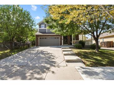 Two-story house with gray siding, brick accents, and a landscaped yard at 385 N Flat Rock St, Aurora, CO 80018