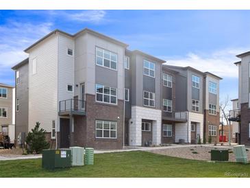 Modern three-story townhome with brick and light gray siding at 455 Interlocken Blvd # 101, Broomfield, CO 80021