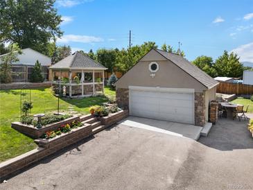 Landscaped backyard with gazebo, detached garage, and stonework at 7302 Upham Ct, Arvada, CO 80003